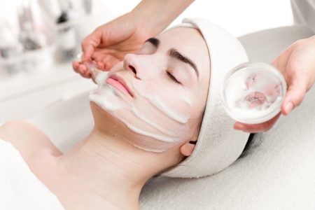 Young woman facial peeling mask applying in beauty parlour